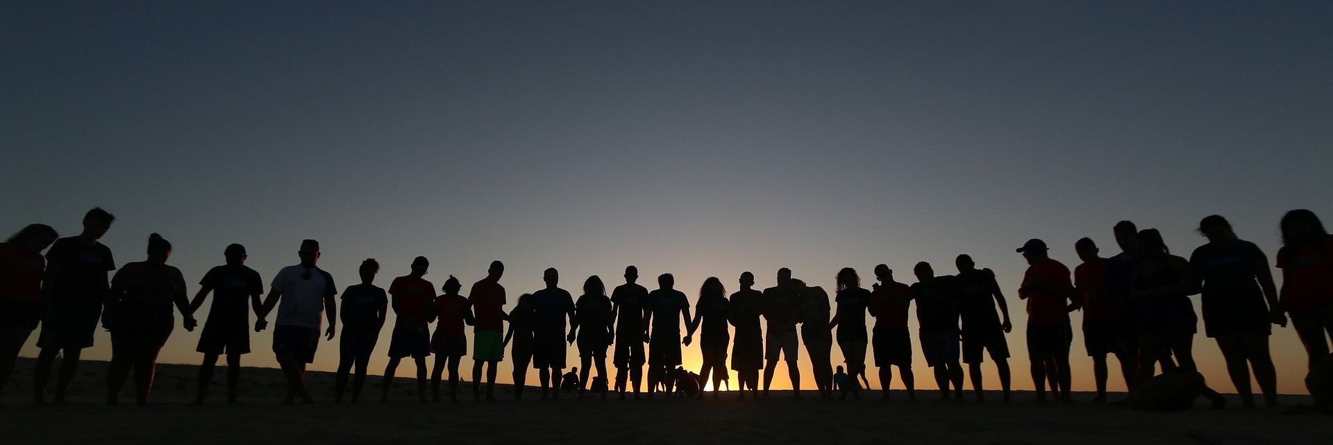 Eine Personengruppe betrachtet den Sonnenuntergang.