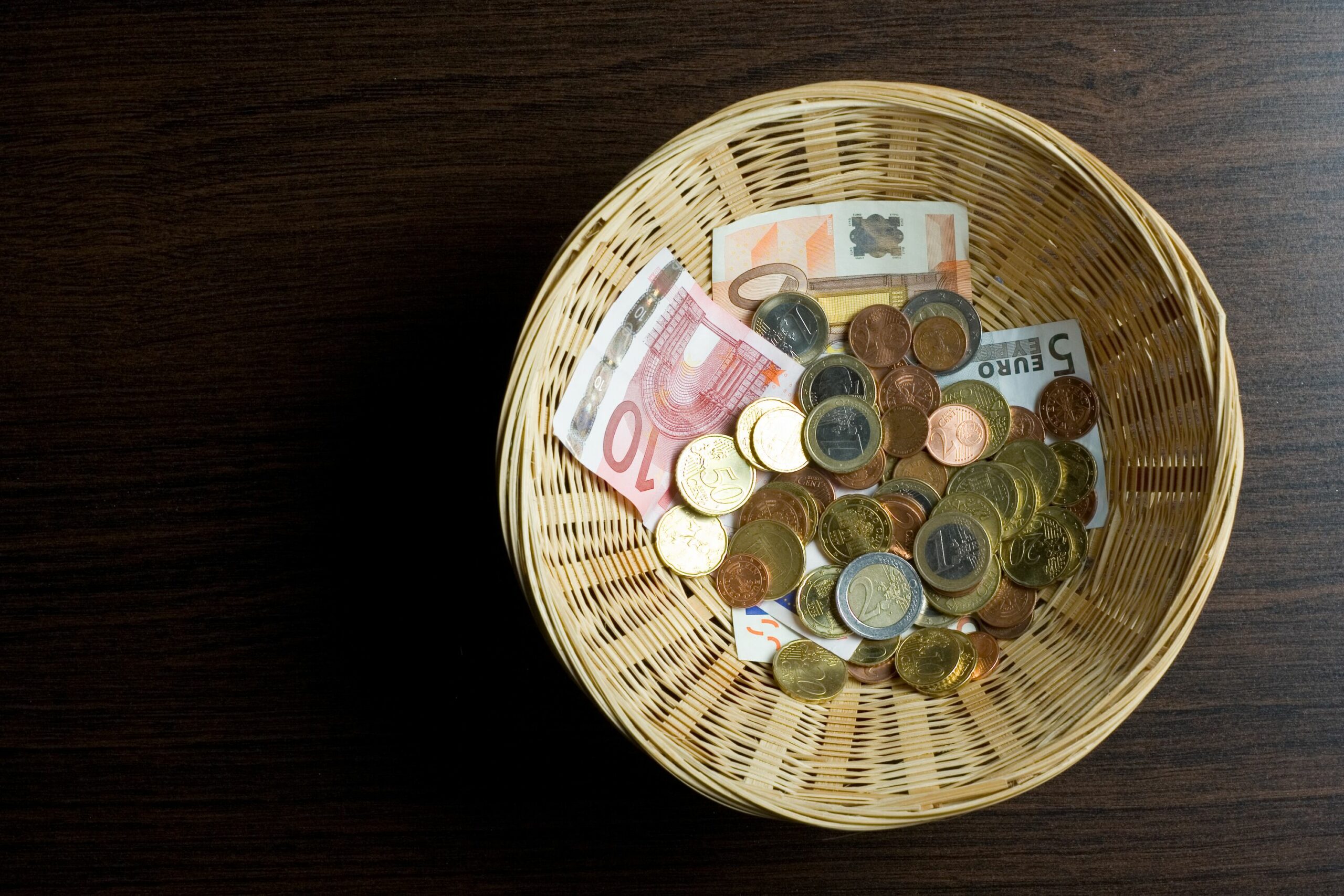 Ein Korb mit Münzen und Geldscheinen als Spende